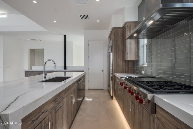 kitchen featuring sink, wall chimney exhaust hood, stainless steel appliances, light stone counters, and backsplash