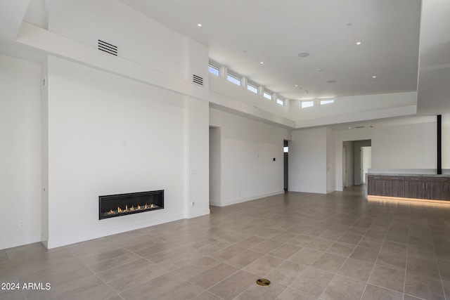 unfurnished living room featuring tile patterned flooring and a high ceiling