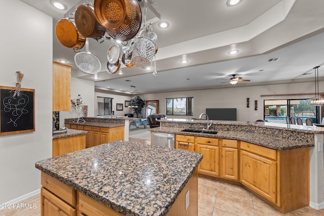 kitchen with sink, kitchen peninsula, a center island with sink, dishwasher, and ceiling fan with notable chandelier