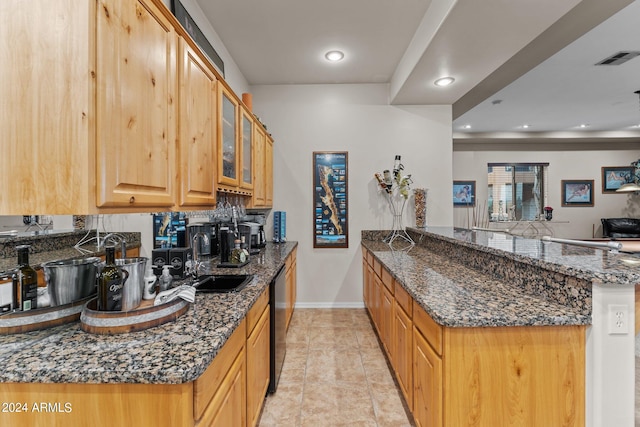 kitchen with dark stone counters, black dishwasher, light tile patterned flooring, sink, and kitchen peninsula