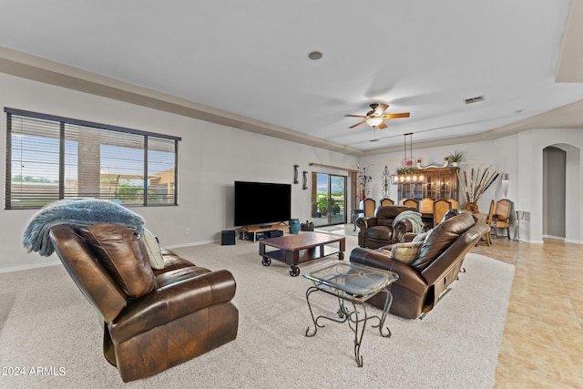 tiled living room with ceiling fan with notable chandelier and ornamental molding