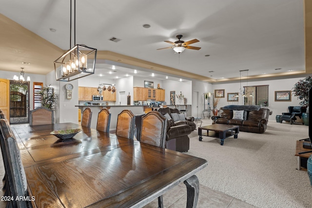 dining room with ceiling fan with notable chandelier and light colored carpet