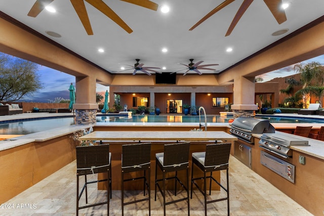 patio terrace at dusk featuring an indoor pool, area for grilling, ceiling fan, and a grill