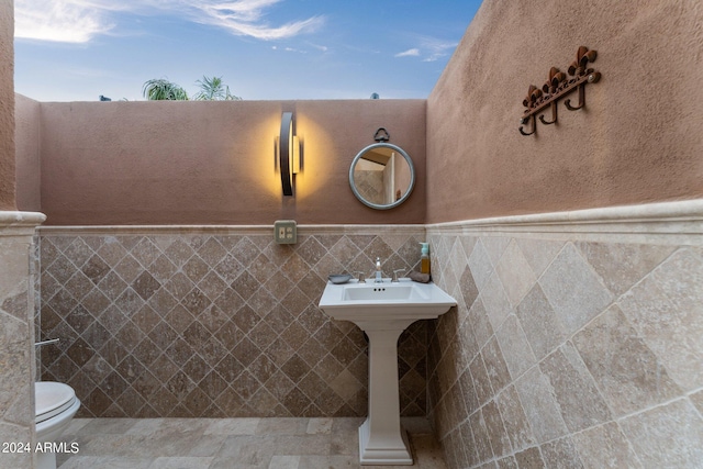 bathroom with tile walls and toilet