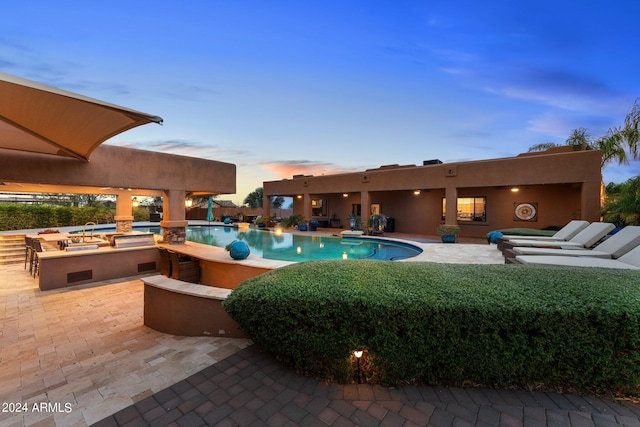 pool at dusk featuring a patio and an outdoor fire pit