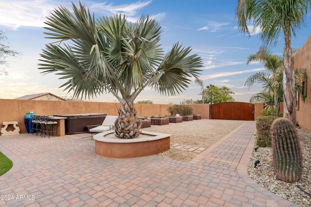 patio terrace at dusk featuring a hot tub and an outdoor fire pit