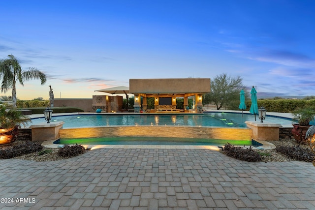 pool at dusk with a patio area