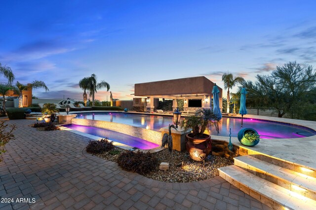 pool at dusk with a patio and a gazebo