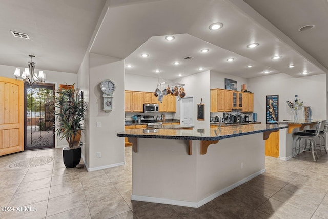 kitchen featuring a breakfast bar, dark stone countertops, a chandelier, and appliances with stainless steel finishes