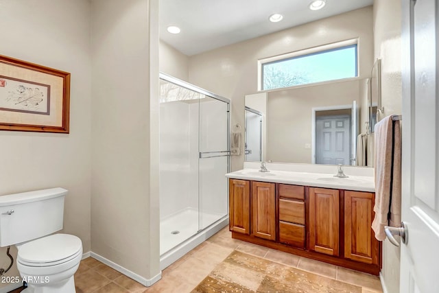 bathroom featuring a sink, toilet, double vanity, and a shower stall