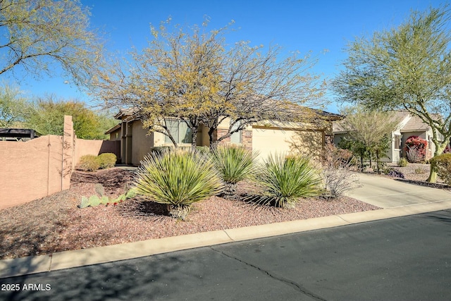 view of front of property featuring stucco siding, an attached garage, concrete driveway, and fence