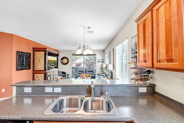 kitchen featuring dark countertops, visible vents, open floor plan, brown cabinetry, and a sink