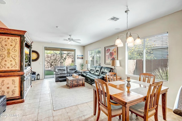 dining area featuring light tile patterned flooring, ceiling fan with notable chandelier, and visible vents