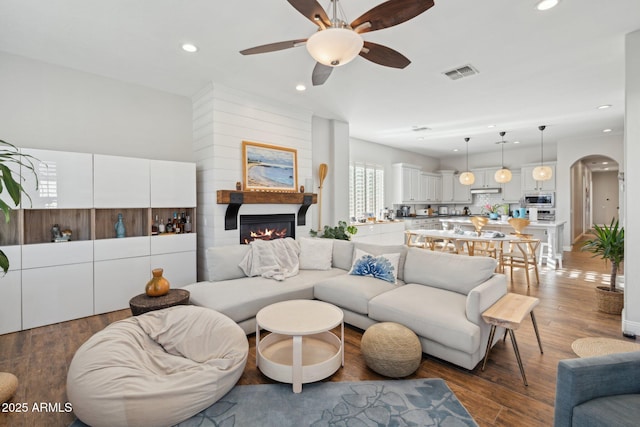 3917 E Patrick Ln, Phoenix, AZ 85050 - living room with ceiling fan, arched walkways, a glass covered fireplace, recessed lighting, and wood finished floors