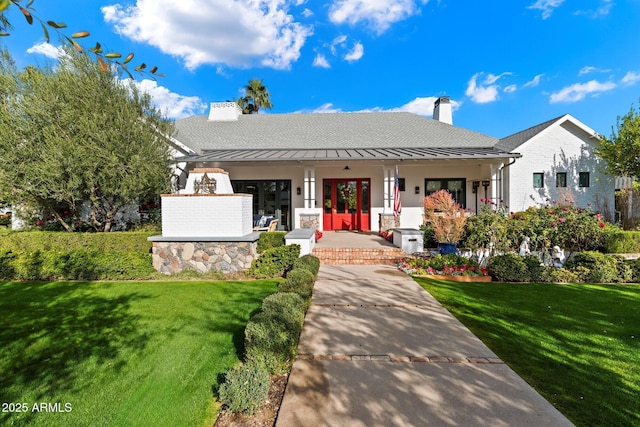 view of front of property featuring covered porch, a front yard, and french doors