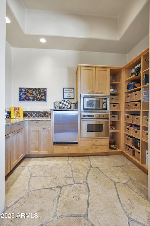 kitchen with light brown cabinetry and appliances with stainless steel finishes