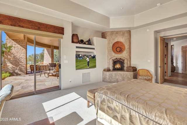 carpeted bedroom featuring access to exterior and a large fireplace