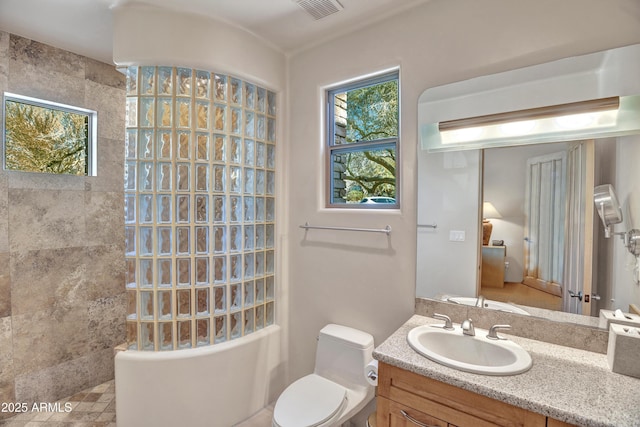 bathroom with vanity, tiled shower, and toilet