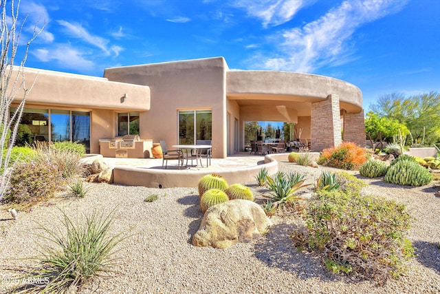 rear view of house with exterior kitchen and a patio area