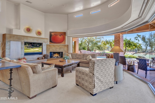 carpeted living room featuring a tiled fireplace and a high ceiling