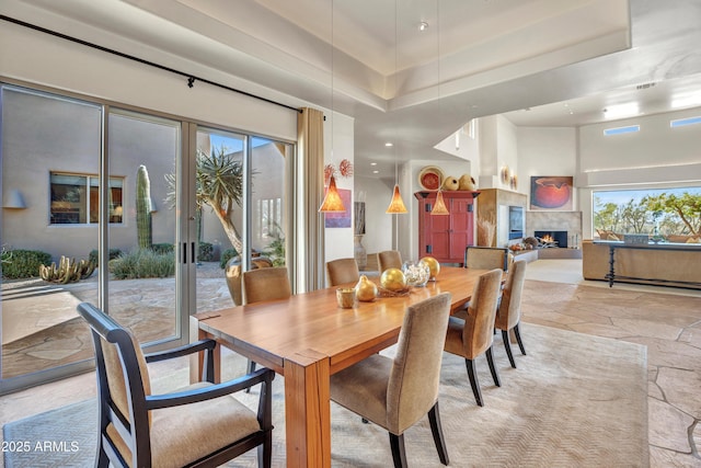 dining area featuring a high end fireplace and a high ceiling