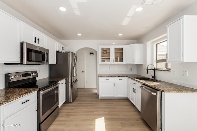 2112 S 160th Dr, Goodyear, AZ 85338 - kitchen with appliances with stainless steel finishes, recessed lighting, glass insert cabinets, arched walkways, and tasteful backsplash