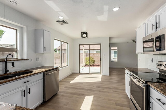 2112 S 160th Dr, Goodyear, AZ 85338 - kitchen featuring stainless steel appliances, backsplash, dark stone counters, recessed lighting, and light wood finished floors