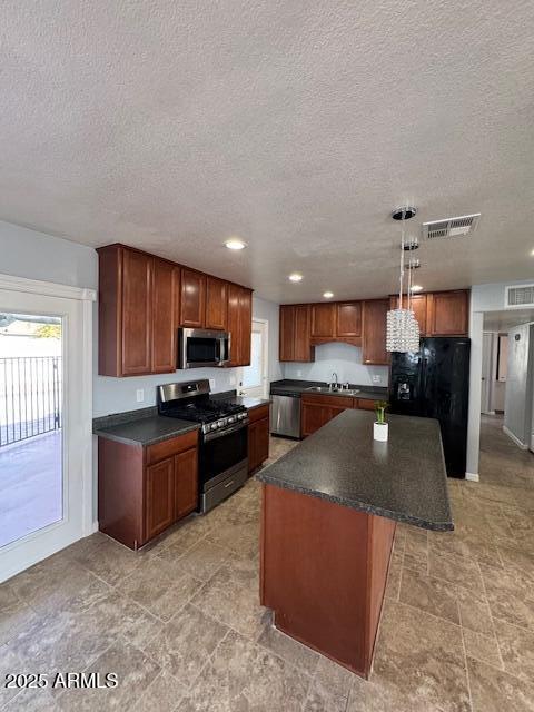 kitchen with a kitchen island, sink, hanging light fixtures, a textured ceiling, and stainless steel appliances