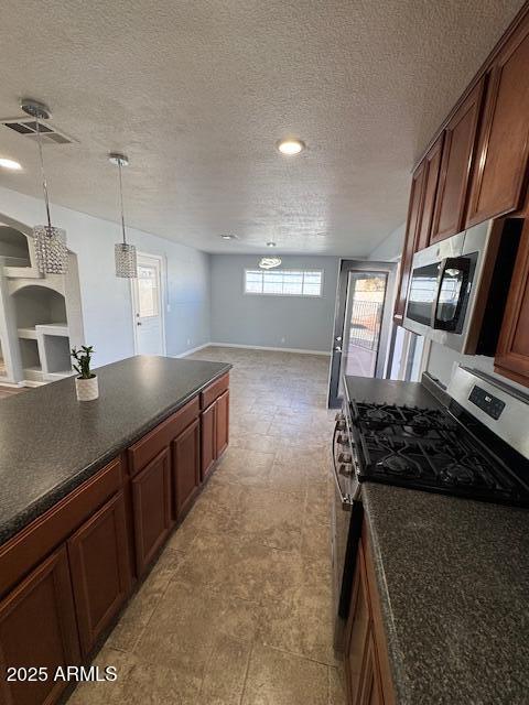 kitchen featuring a textured ceiling, appliances with stainless steel finishes, and hanging light fixtures