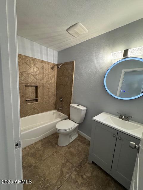 full bathroom featuring toilet, a textured ceiling, tiled shower / bath combo, and vanity