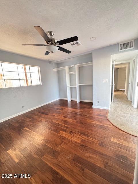 unfurnished bedroom featuring ceiling fan, a closet, dark hardwood / wood-style floors, and a textured ceiling