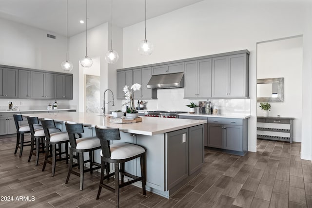 kitchen featuring gray cabinetry, decorative light fixtures, a kitchen breakfast bar, and a large island with sink