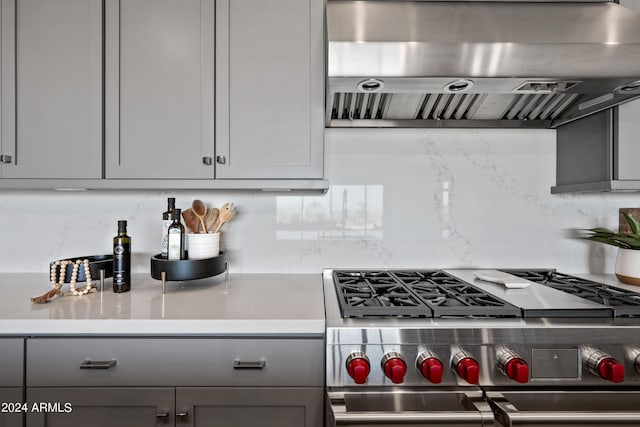 kitchen featuring gray cabinetry, extractor fan, stainless steel range, and decorative backsplash