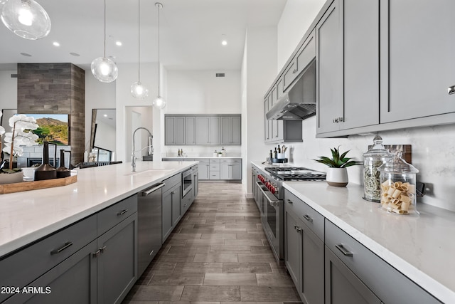 kitchen with sink, light stone counters, gray cabinets, pendant lighting, and stainless steel appliances