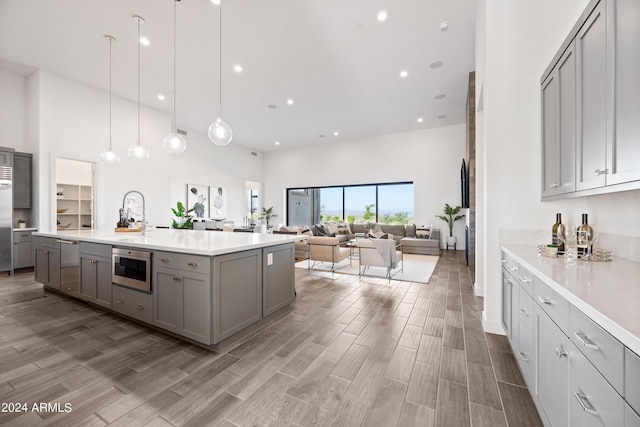 kitchen featuring pendant lighting, sink, appliances with stainless steel finishes, gray cabinetry, and a high ceiling