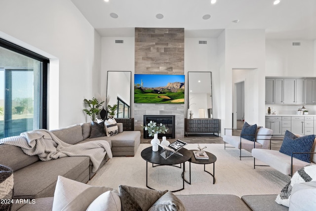 living room with a towering ceiling and a tiled fireplace