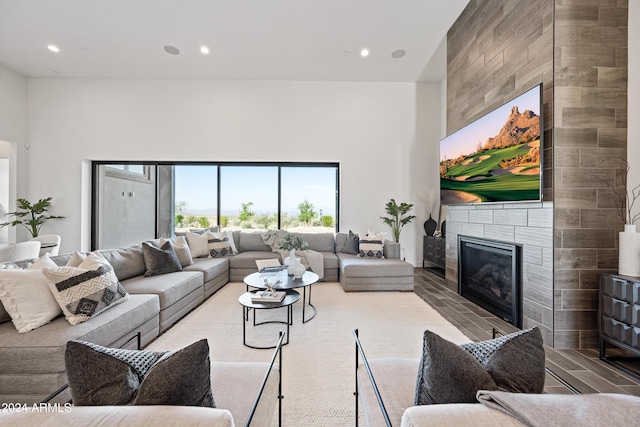 living room featuring light wood-type flooring, a fireplace, and a high ceiling