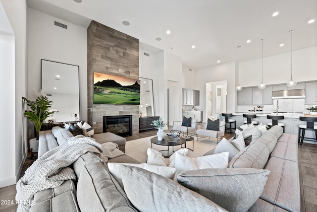 living room with a tiled fireplace, hardwood / wood-style floors, and a towering ceiling