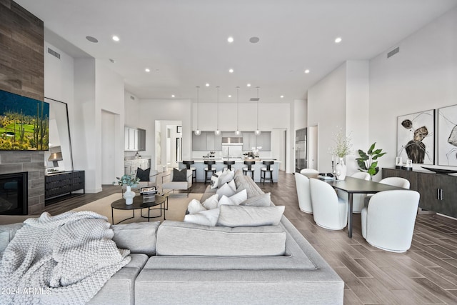 living room featuring a high ceiling, a large fireplace, and hardwood / wood-style floors