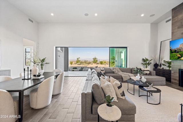 living room featuring light hardwood / wood-style floors, a tile fireplace, and a high ceiling