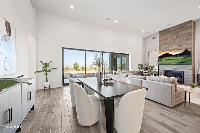 dining area with a tiled fireplace and a high ceiling