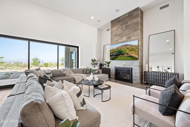 living room featuring a high ceiling, a tiled fireplace, and light tile patterned flooring