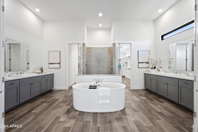 bathroom with a towering ceiling, shower with separate bathtub, and hardwood / wood-style floors