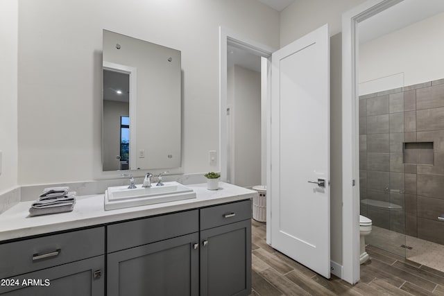 bathroom featuring vanity, tiled shower, and toilet