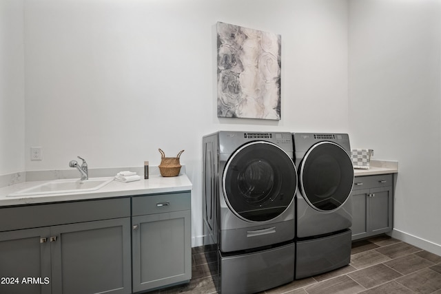 clothes washing area featuring sink, cabinets, and independent washer and dryer