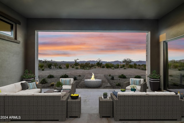 patio terrace at dusk with a mountain view and an outdoor living space with a fire pit