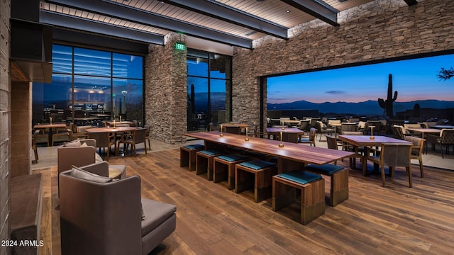 dining space with a high ceiling, wood-type flooring, and beam ceiling