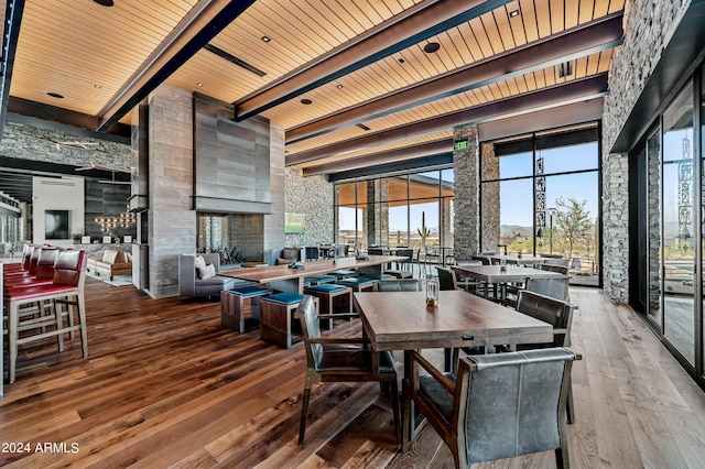 dining room with a high ceiling, light wood-type flooring, wooden ceiling, and beam ceiling