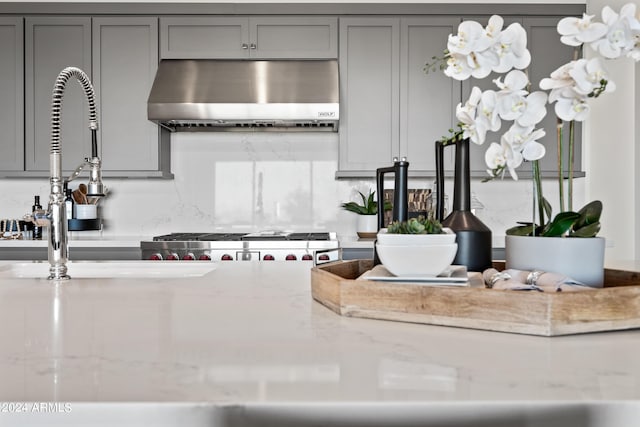 kitchen with gray cabinets, extractor fan, and light stone counters