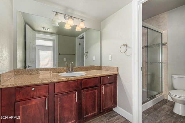 bathroom featuring a shower with door, toilet, and vanity